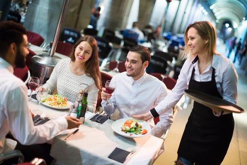 Waiter balancing a tray of drinks in a busy restaurant – hospitality hiring solutions