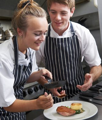 Kitchen staff preparing multiple dishes for service – hospitality job board