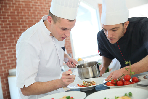 Kitchen porter washing large pots in a busy hotel kitchen – catering workforce