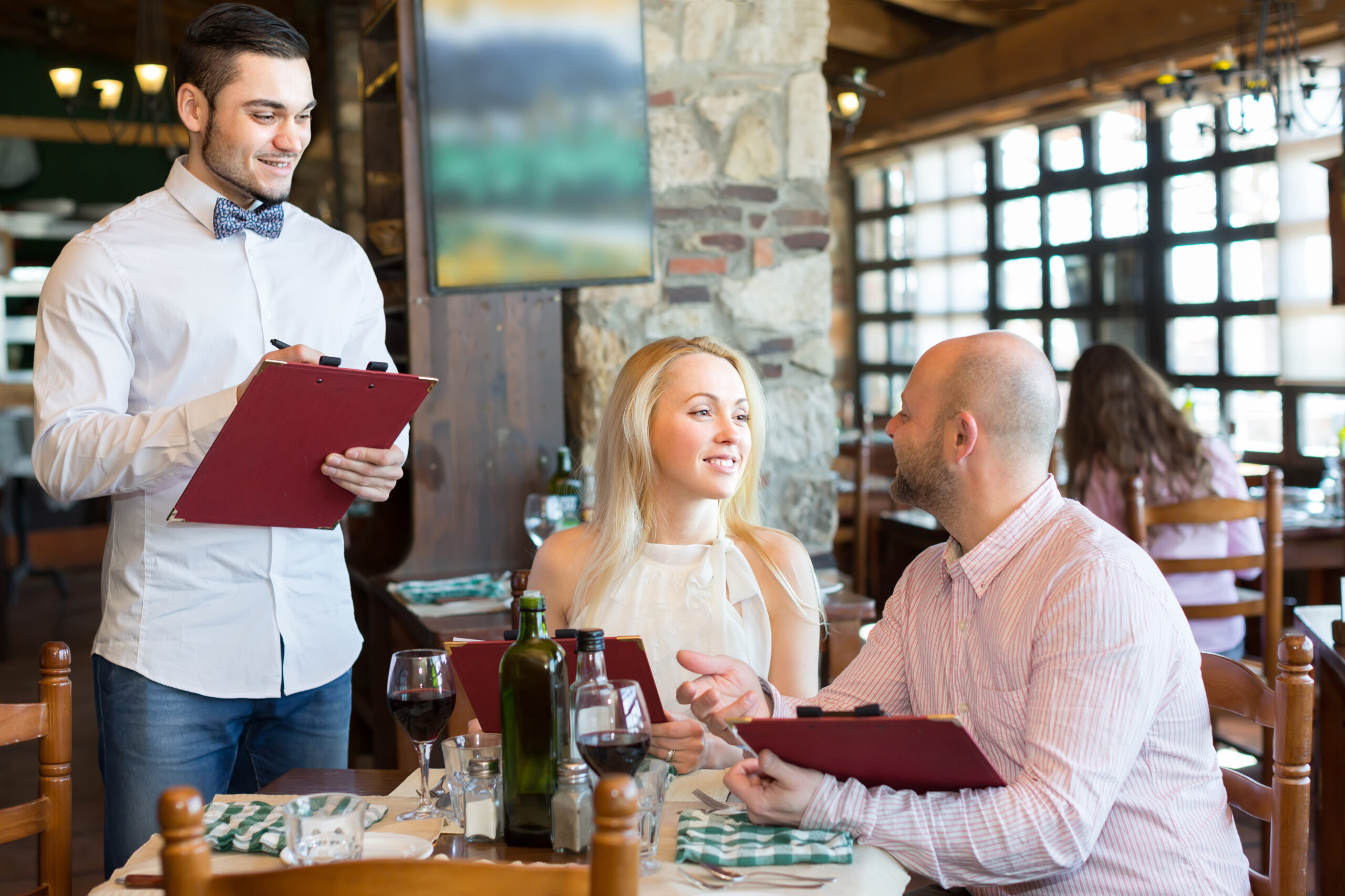 Cheerful,Young,Male,Waiter,Serving,Restaurant,Guests,At,Table.,Selective